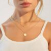 Layered gold necklace with fine chains, bar pendant and round disc charm