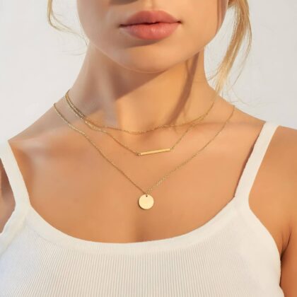 Layered gold necklace with fine chains, bar pendant and round disc charm