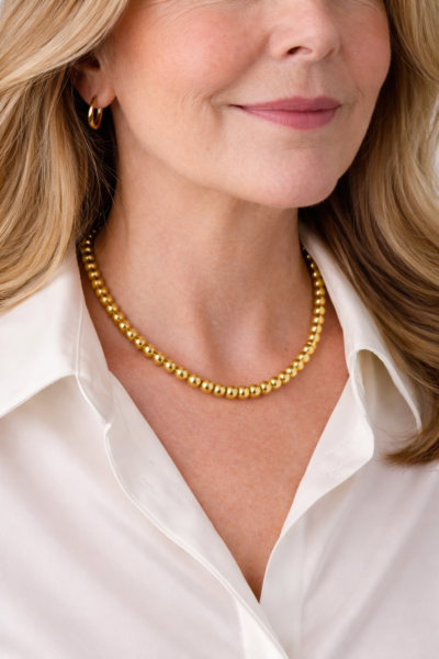 gold bead necklace Woman wearing gold stainless steel bead necklace with white blouse close-up