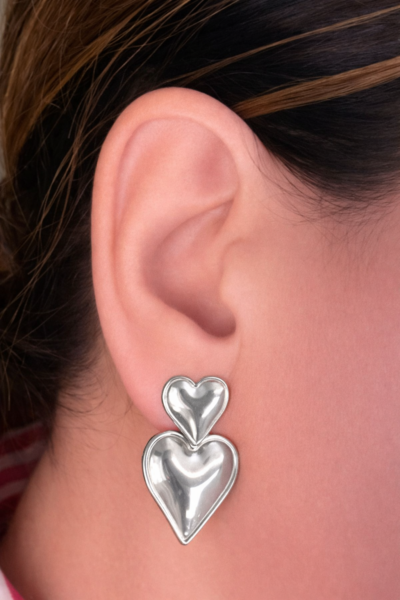 Woman wearing silver double heart drop earrings made from stainless steel
