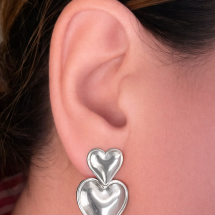 Woman wearing silver double heart drop earrings made from stainless steel