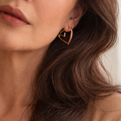 Woman wearing gold plated stainless steel open heart hoop earring, elegant and timeless jewelry style