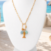 Ibiza fish necklace Gold stainless steel Ibiza fish necklace with blue charms on white mannequin against Ibiza beach background.