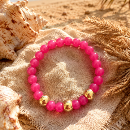 Pink Paradise Bracelet Bright pink elastic bracelet with acrylic beads and gold accents styled on a beachy summer background
