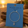 Sweet7 silver stainless steel elastic beaded bracelet with shell charm.
