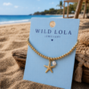Starfish Shell Bracelet β Gold Stainless Steel Gold elastic bracelet with stainless steel beads, starfish charm and shell detail displayed on a beach-inspired background.