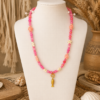 Ibiza Pink Turtle Necklace Pink Ibiza necklace with turtle beads, star details and gold fish charm displayed on a white mannequin in a boho setting.