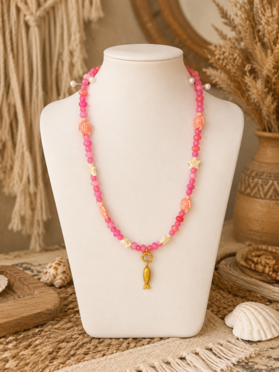 Ibiza Pink Turtle Necklace Pink Ibiza necklace with turtle beads, star details and gold fish charm displayed on a white mannequin in a boho setting.