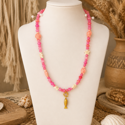 Ibiza Pink Turtle Necklace Pink Ibiza necklace with turtle beads, star details and gold fish charm displayed on a white mannequin in a boho setting.