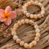 Handmade beige acrylic bead bracelet with starfish accents displayed on driftwood.